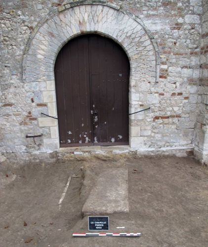 Vue d'ensemble du sondage lors de la découverte des sarcophages au pied du portail de l'église actuelle de la Chapelle Saint-Mesmin. Le couvercle de sarcophage est sur la droite, tandis que la cuve est visible sur la gauche (crédits : Pôle d'archéologie, 