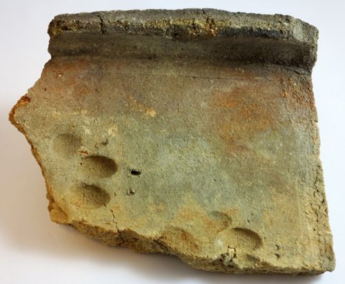 Tegula du haut Moyen Âge retrouvée sur le site de la "Voie Nouvelle" à Saran. Seul un rebord est ici conservé. On observe les traces de pas d'un chien, passant sur la tuile en cours de séchage après son façonnage (Cliché Isaac Osses ; 2015)