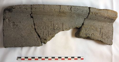 Fragment latéral de tegula du haut Moyen Âge, avec écriture cursive en latin, découvert sur le site de Saran "Voie Nouvelle" (crédits : Pôle d'Archéologie, 2014)