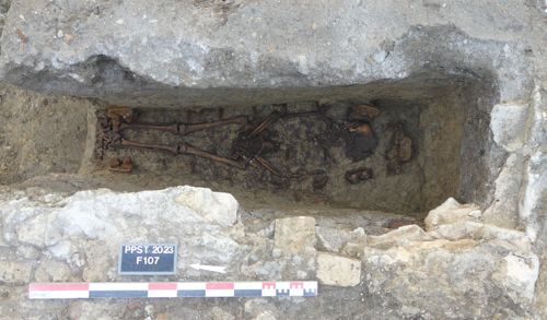  Vue en plan d'une sépulture avec l’individu inhumé en place. Autour de lui, les poignées et clous de cercueil sont visibles, ainsi que les vestiges d’une partie de la maçonnerie qui surmontait la tombe (PAVO, 2023)
